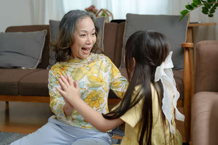 Asian portrait, grandma and granddaughter doing leisure activities and hugging to show their love and care for each other.の写真素材