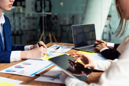 Male businessman holding pen to take notes summarizing marketing strategy with female colleagues in meeting, teamwork, investment planning.の写真素材