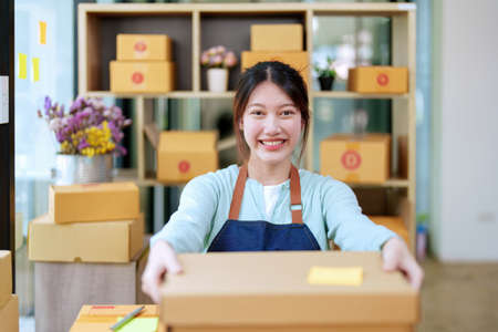Portrait of a business woman, sme packing products in boxes and showing delivery to customers...