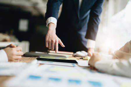 Male businessman pointing to documents summarizing marketing strategy with female colleagues in...