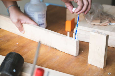 Woodworking operators are using glue to put together the wood parts to assemble and build a wooden...