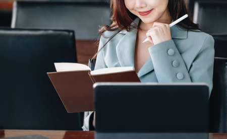 Asia woman entrepreneur or businesswoman showing a smiling face while reading a book developing...