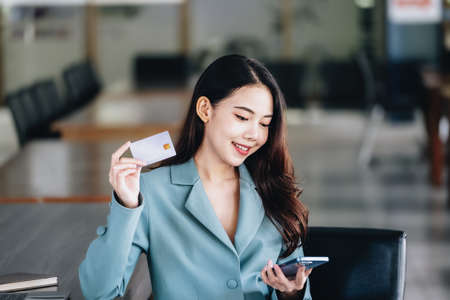 Online Shopping and Internet Payments, Beautiful Asian women are using their credit cards and mobile phones to shop online or conduct errands in the digital worldの写真素材
