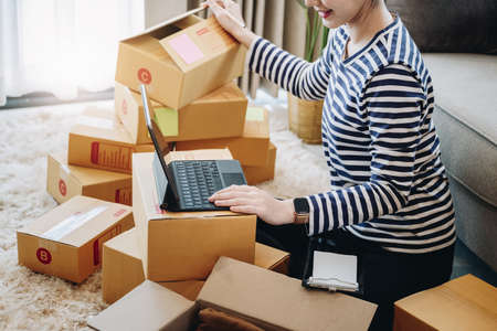 Online business idea, beautiful girl at home checking the products ordered by the customers on the...