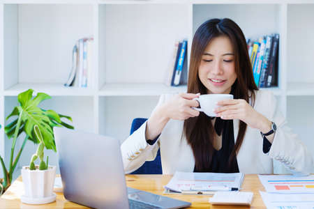 Accountant, businessman, Portrait of Asian female employee taking a coffee break after closing a...