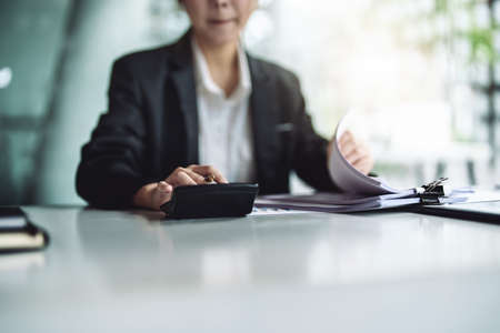 accountant, Auditor, Self-Employed, Finance and Investment, tax calculation and budget, Asian female entrepreneur using a calculator to calculate. Company business results documentの写真素材