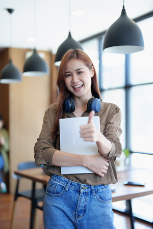 A portrait of a young Asian woman with a smiling face looking for a textbook in the library.の写真素材