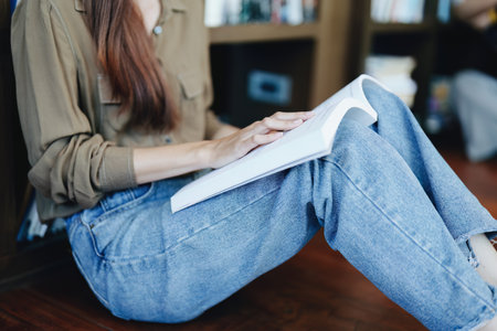 A portrait of a young Asian woman with a smiling face looking for a textbook in the library.の写真素材