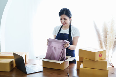 Starting small business entrepreneur of independent Asian woman smiling with cheerful success of online marketing package box items and SME delivery concept.の写真素材