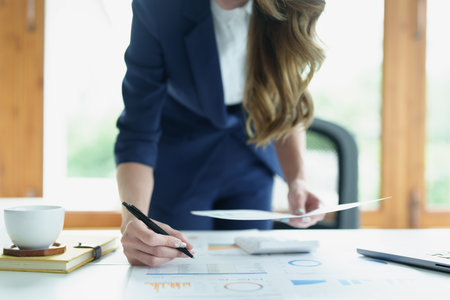 Portrait of a thoughtful Asian businesswoman looking at financial statements and making marketing plans using a computer on her desk.の写真素材