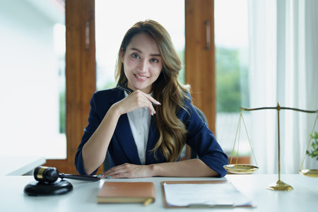 Portrait of a young Asian lawyer studying a lawsuit for a client using notebooks and paperwork on a desk.の写真素材