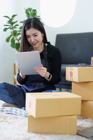 Startup small business entrepreneur of freelance Asian woman smiling and using tablet computer with...