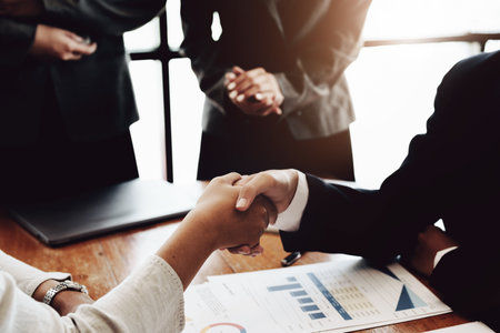 The handshake symbolizes, Group of entrepreneurs showing signs of merger to enhance their...