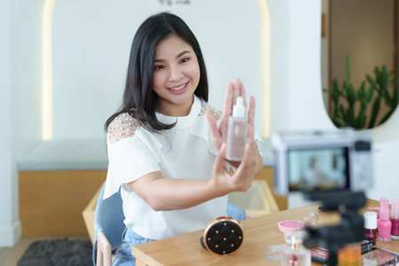 online trading business, a beautiful young woman working independently at home reviewing cosmetic products through the camera to customers to increase their interest in making a purchase decision.の写真素材