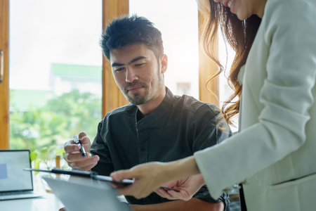 A portrait of a female marketer and a male salesperson discussing how to increase sales by investing in new products to expand marketing using documents and computers in working, new idea product.の写真素材