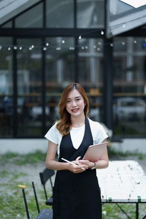 Starting and opening a small business, a young Asian woman showing a smiling face holding a tablet...