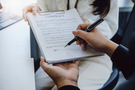 Guarantee, Mortgage, agreement, contract, Signing, Male client holding pen to reading agreement document to sign land loan with real estate agent or bank officerの写真素材