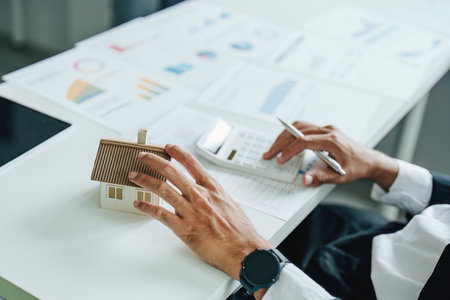 Bank staff at the Mortgage Department are working on paperwork and using a loan interest rate calculator for clients to assess their investment potential.の写真素材