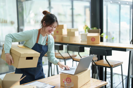 A portrait of a small startup, an SME owner, an Asian female entrepreneur checking orders to arrange the produce before packing the products in the inner boxes with the customers. Freelance concepts.の写真素材