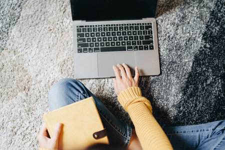Portrait of a young Asian woman using a computer on the sofa.の写真素材