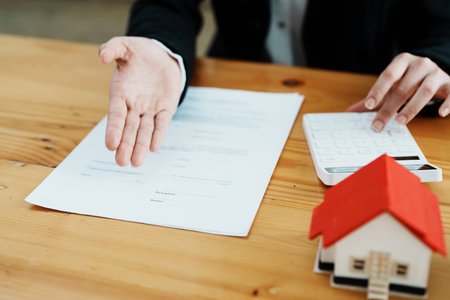 Guarantee, mortgage, contract, contract, signed, real estate agent or bank officer holding a calculator, submits a bid with a customer to buy a home before signing to make a deal.の写真素材