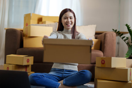 Portrait of a small startup Asian female entrepreneur SME owner picking up product before packing it...