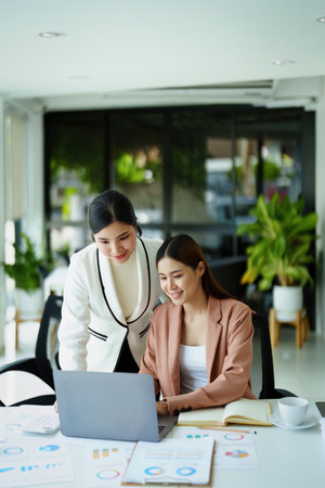 A portrait of two female employees using computers while working to analyze their finances and increase their marketing strategies to combat their competitors.の写真素材