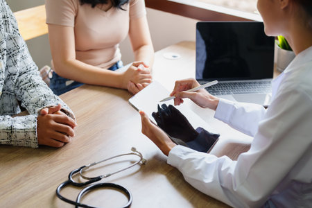 Portrait of a doctor advising clients on health issues holding a tablet to work and talking to patients who come to treatment.の写真素材