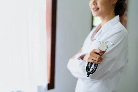 Portrait of an Asian female doctor smiling happily holding a stethoscope after a break from work.の写真素材