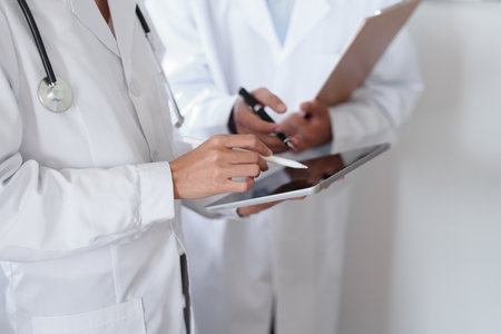 Portrait of an Asian female doctor and male doctor using a tablet to discuss patient problems before treatment.の写真素材