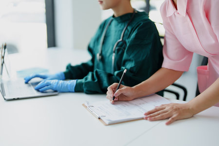 Portrait of Asian doctors and nurses using computers and documents to view patient information to...