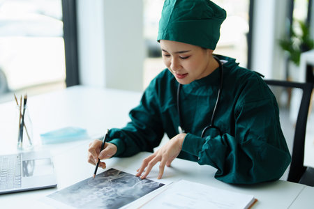 Portrait of an Asian doctor looking at patient X-ray film to analyze the abnormality of the clients body.の写真素材