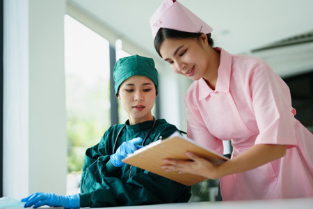 Portrait of Asian doctors and nurses using computers and documents to view patient information to analyze symptoms before treatmentの写真素材
