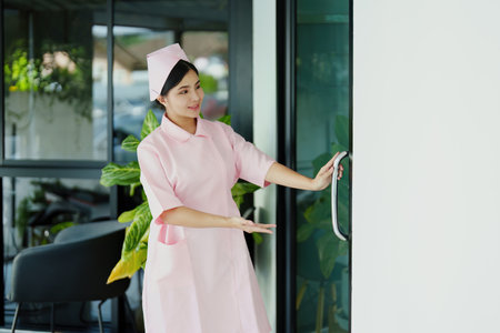 Portrait of a young nurse in a pink dress smiling happily.の写真素材