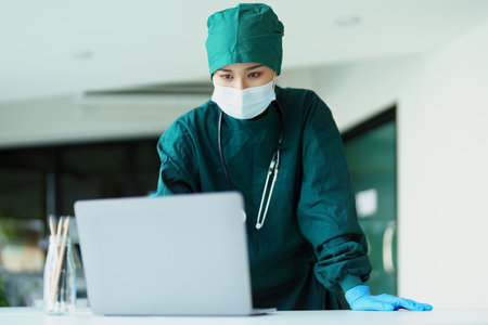 Portrait of an Asian doctor using a computer to look at patient data to analyze symptoms before treatment.の写真素材
