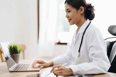 Portrait of an Asian female doctor using a computer and tablet to work.の写真素材