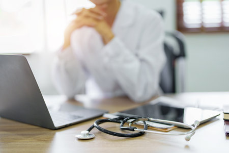 An Asian female doctor uses a computer while showing concern about patient information.の写真素材