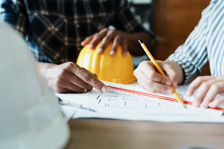 Engineers are consulting the team to design an architectural structure for clients with blueprints and building models to work at office.の写真素材