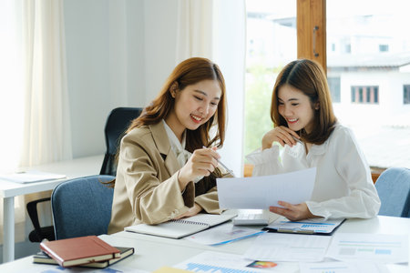 Negotiation, Analysis, Discussion, Portrait of an Asian woman economist and marketer pointing to a financial data sheet to plan investments to prevent risks and losses for the company.の写真素材