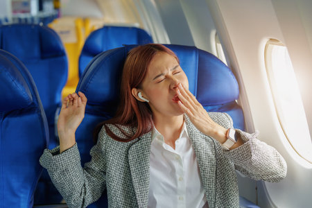 Portrait of a successful Asian businesswoman or entrepreneur in a formal suit on an airplane in business class waking up from resting between flights.の写真素材
