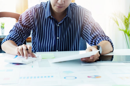 businessman hands using a calculator to check company finances and earnings and budget. calculating...