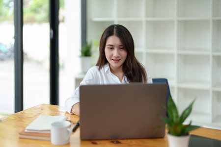 Portrait of a beautiful Asian businesswoman at work office desk with laptop computer in office.の写真素材