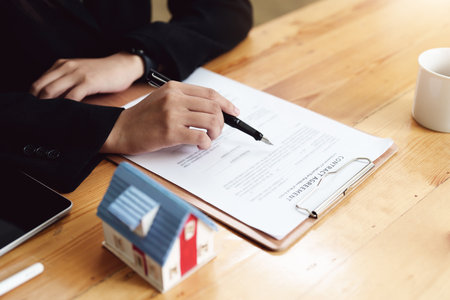 Asian female bank employee asking a customer to read the contract before signing to agree to buy a house, real estate concepts.の写真素材