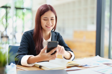Asian businesswoman using the phone to contact a business partner.の写真素材