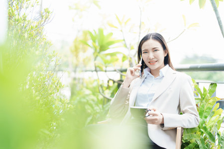 Portrait of a business woman talking on the phone and drinking coffee.の写真素材