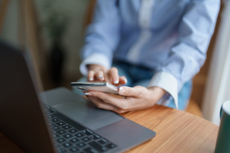 Portrait of a beautiful Asian teenage girl using her phone and computer sitting on the sofa at home.
