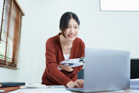 financial, Planning, Marketing and Accounting, portrait of Asian employee checking financial statements using documents and computer at work..の写真素材
