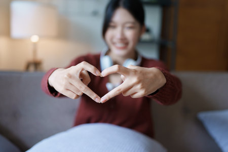 Portrait of beautiful Asian woman showing heart symbol with finger.の写真素材