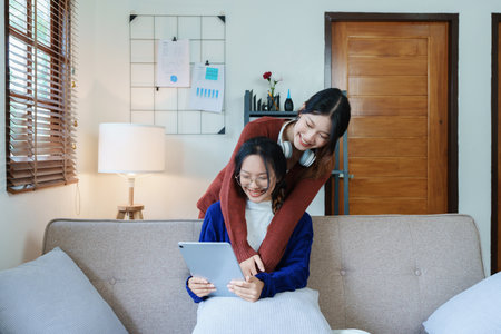 lgbtq, lgbt concept, homosexuality, portrait of two asian women enjoying together and showing love for each other while using tablet.の写真素材
