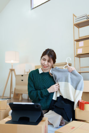 Starting small business entrepreneur of independent young Asian woman online seller using a tablet computer showing products to a customer before making a purchase decision. SME delivery concept.の写真素材